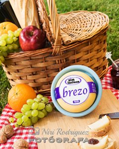 Queso Brezo de la marca LORAN. Una cesta de picnic con manzana, naranjas, uvas y pan.