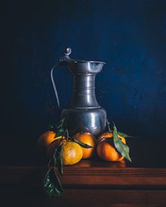 Bodegón de mandarinas y una jarra de metal.
