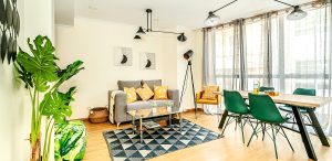 Fotografía inmobiliaria de un salón con sofá de color marrón y cojines amarillos, alfombra con formas de triángulos.