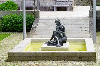 Esculturas de una pareja en medio de una pileta de agua.
