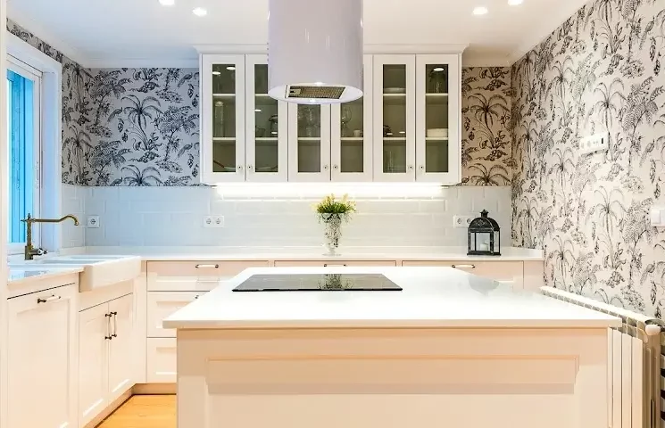 Sesión de fotografía inmobiliaria de una cocina moderna color blanco, con isla en el centro y campana que sale del techo.